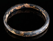 A LATE ROMAN/BYZANTINE GLASS BRACELET Circa 4th-8th century AD. Opaque dark glass (black in appearance); semicircular in section with flat inner side....