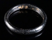 A LATE ROMAN/BYZANTINE GLASS BRACELET Circa 4th-8th century AD. Opaque dark glass (black in appearance); semicircular in section with flat inner side....