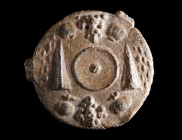 A ROMAN LEAD VOTIVE ROUNDEL WITH TABLE OFFERINGS Circa 1st-3rd century AD. Centrally a phiale (libation bowl) surrounded by pomegranates, grapes, and ...