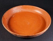 A ROMAN RED SLIP WARE POTTERY BOWL Circa 2nd-3rd century AD. Shallow bowl with low ring foot. Small crack on the rim with a small piece broken and rea...