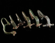 A GROUP OF SIX BYZANTINE BRONZE BROOCHES WITH BENT FOOT Circa 6th-7th century AD. Cast bow brooches with folded foot (umgeschlagenem Fuß), mostly with...