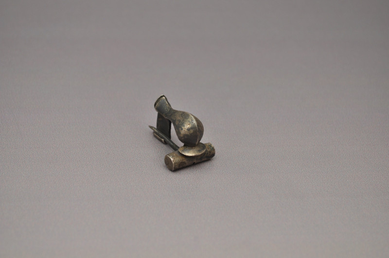 ARQUEOLOGÍA. ROMA. Fíbula de rodilla (ss. II-III d.C.). Plata. Longitud 3 cm.