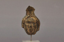 ARQUEOLOGÍA. ROMA. Remate de asa en forma de rostro (ss. I-IV d.C.). Bronce. Altura 7 cm. Adherido a la peana (descripción de la cartela de la peana n...