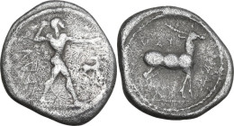 Greek Italy. Bruttium, Kaulonia. AR Drachm, c. 475-425 BC. Obv. Apollo advancing right, holding branch; small daimon running right on Apollo's left ar...