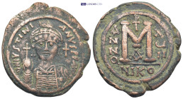 JUSTINIAN I (527-565). Follis. Nicomedia. (19 Gr. 36mm.)
Helmeted and cuirassed bust facing, holding globus cruciger and shield decorated with horsema...
