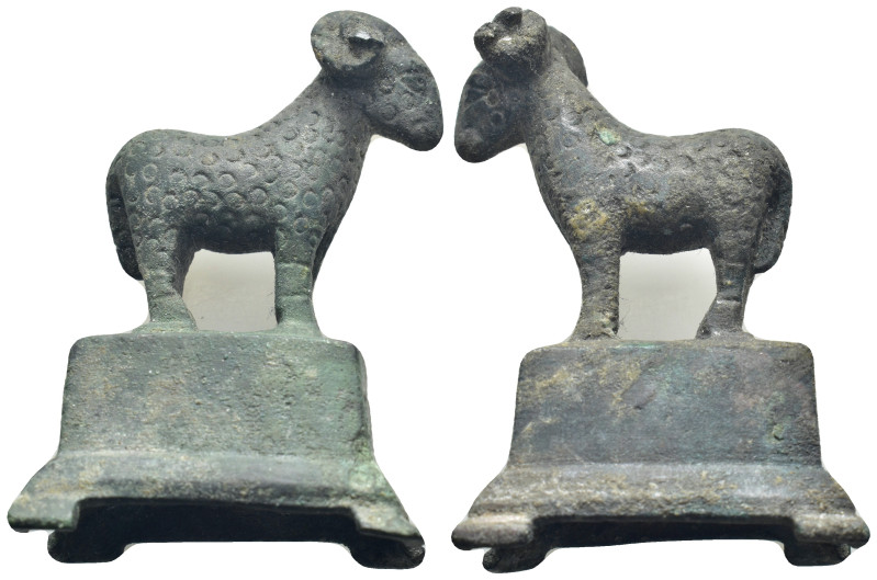 Bronze figure of a goat standing on a rectangular base, head turned to the side,...