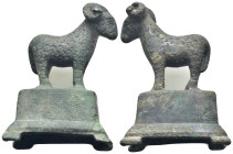 Bronze figure of a goat standing on a rectangular base, head turned to the side, horns curling round ears, finely detailed wool over the body. (62mm, ...