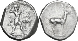 Greek Italy. Bruttium, Kaulonia. AR Stater, 475-425 BC. Obv. Apollo striding right, holding branch; small daimon running right on Apollo's left arm; t...