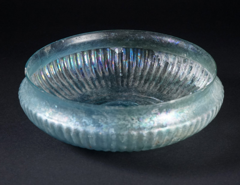 A ROMAN PALE BLUE-GREEN GLASS FINELY RIBBED BOWL
Circa early 1st century AD.
A...