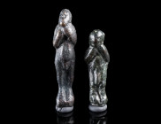 TWO ROMAN BRONZE FIGURAL AMULET PENDANTS
Circa 2nd-3rd century AD.
Both showing a male figure holding his hands to the chest/face. The genitals are ...