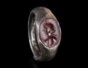 A ROMAN SILVER RING WITH A CARNELIAN INTAGLIO
Circa 1st-2nd century AD.
Solid silver ring with an oval carnelian intaglio depicting a nude male bust...