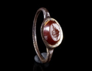A ROMAN GILT BRONZE RING WITH A CARNELIAN INTAGLIO
Circa 2nd-3rd century AD.
Delicate ring with offset shoulders; the raised bezel is set with an ov...
