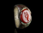 A ROMAN BRONZE RING WITH A CARNELIAN INTAGLIO
Circa 1st-2nd century AD.
Ring with an oval intaglio depicting a hand with a string (?) around it. Pos...
