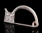 AN EARLY THRACIAN SILVER FIBULA OF THE 'THESSALIAN TYPE'
Circa 6th century BC.
Richly decorated bow brooch with trapezoid catch-plate. The foot term...