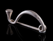 AN IRON AGE/EASTERN CELTIC SILVER BOW FIBULA
Circa 4th-3rd century BC.
Thracian Type fibula. Made of one piece with spring and pin; the foot termina...
