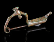 AN IRON AGE BRONZE CERTOSA-TYPE FIBULA
Circa 6th-5th century BC.
The bow decorated with three knobs; the foot with incised lines terminates in a fur...