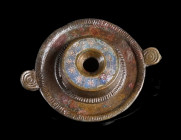 A ROMAN ENAMELLED BRONZE DISK BROOCH
Circa 2nd century AD.
The raised centre decorated with a ring of millefiori flowers on a blue ground. With a fi...