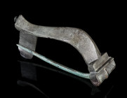 A LARGE ROMAN BRONZE KNEE BROOCH
Circa 2nd-3rd century AD.
With facetted bow and hinged pin.
L 50 mm

Acquired on the UK art market.