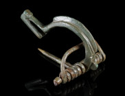 A LATE ANTIQUE/GERMANIC BRONZE KNOB-BOW BROOCH
Circa 4th-5th century AD.
Variant of the so-called 'Bügelknopffibel'. The arched bow with a raised ri...