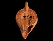 A LATE ROMAN CHRISTIAN OIL LAMP WITH A STAUROGRAM
Circa 4th-5th century AD.
The shoulders are decorated with geometric motifs, the concave discus fe...