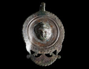 A PENDANT FROM AN EARLY ROMAN MILITARY HORSE HARNESS
Circa 1st century AD.
Circular pendant with pelta-shaped extension and suspension hook; the cen...