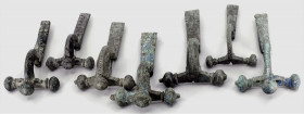 OBJEKTE AUS BRONZE. 
SCHMUCK. 
FIBELN. LOT: 7 Zwiebelkopffibeln Fibeln mit Ringel und geometrischem Dekor, feine braune Patina L.68, 80mm, sowie ohn...