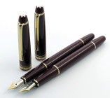 MONTBLANC -Lotto di 2 penne stilografiche- Corpo e cappuccio in resina bordeaux con finiture dorate. Ricarica a cartuccia/converter. Pennini M in oro ...