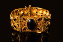 RARE HELLENISTIC GOLD BRACELET WITH GARNETS AND FILIGREE

 Ca. 400 - 300 BC A gold D-shaped bracelet with an intricately designed open-work body. Th...