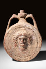 HELLENISTIC TERRACOTTA FLASK WITH GORGON HEAD

 Ca. 300 - 100 BC A mould-formed ornate terracotta flask of a Gorgon head with an elaborate hairstyle...