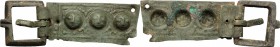 Bronze belt terminal decorated with ebossed faces. Medieval. 79 x 24 mm.