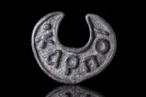 BYZANTINE BREAD STAMP WITH INSCRIPTION KARPOI

 Ca. AD 400 - 600 A moon-shaped bronze bread stamp with rows of Greek letters (Karpoi) within a thick...