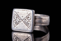 BYZANTINE SILVER RING WITH SQUARE SHAPED BEZEL

 Ca. AD 1200 - 1400 A Medieval silver ring with an internally wide flat band. The exterior is decora...