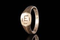 MEROVINGIAN GOLD RING WITH "E" MONOGRAM

 Ca. AD 900 - 1100 A Merovingian gold ring with a round hoop and a flat section widening to form a circular...