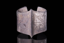 SELJUK SILVER BRACELET WITH FLORAL PATTERN

 Ca. AD 1000 - 1300 An open-type bracelet featuring a prominent central ridge and reinforced edges, givi...