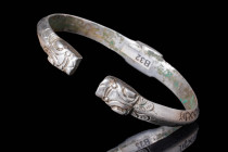SELJUK HEAVY SILVER BRACELET WITH CALLIGRAPHY

 Ca. AD 1000 - 1200 A Seljuk heavy silver bracelet set with a decorated bezel and two finials on the ...