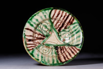 NISHAPUR GLAZED TERRACOTTA DISH WITH PHYTOMORPHIC MOTIF

 Ca. AD 900 - 1100 A Nishapur pottery dish sitting upon an unglazed discoid foot with a sha...
