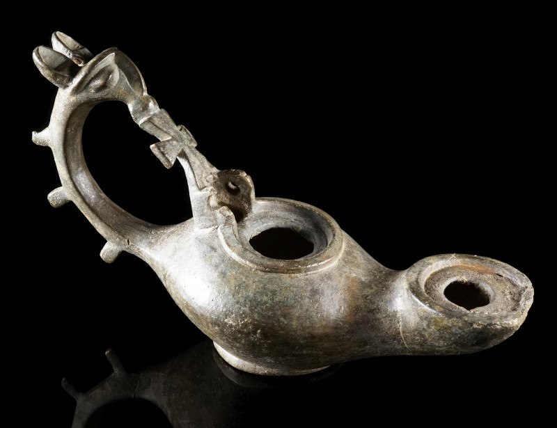 A FINE BYZANTINE BRONZE OIL LAMP WITH A GRIFFIN-HEAD HANDLE
Circa 5th-7th centu...