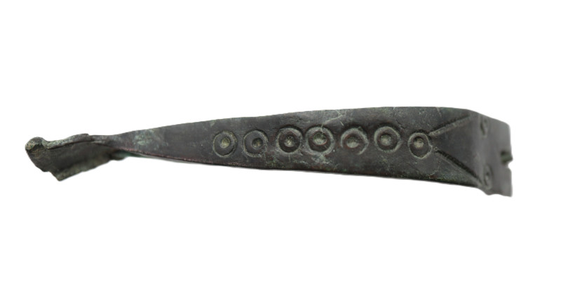 A large bronze fibula with dotted decoration, pin intact, dark green patina; 75....