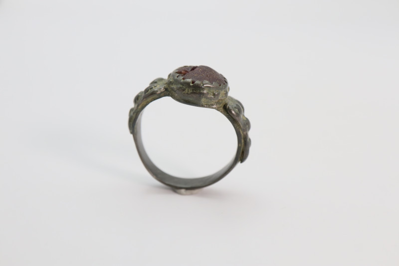 A bronze finger ring with a red stone; green patina intact; 6.20 grams, 27 mm ma...