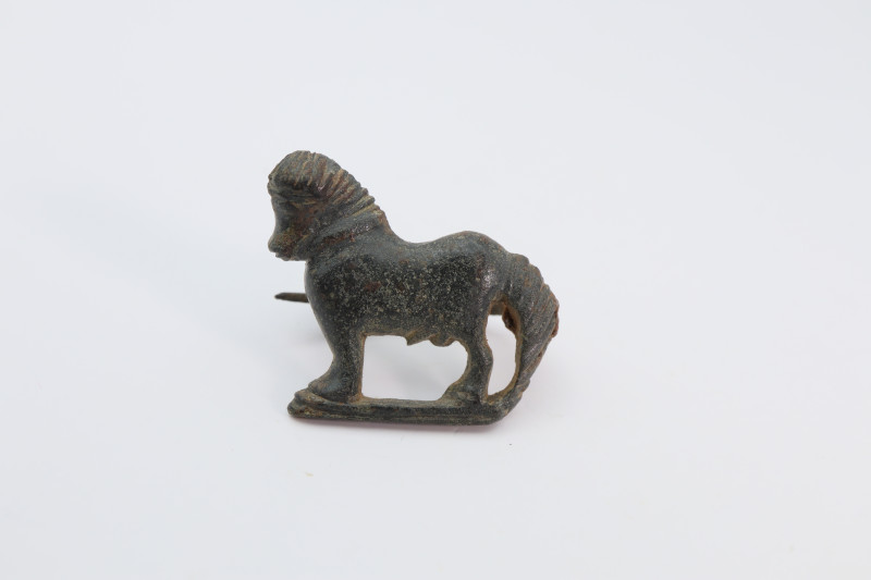 A Roman bronze plate brooch in the form of standing horse on the left. Catch pla...