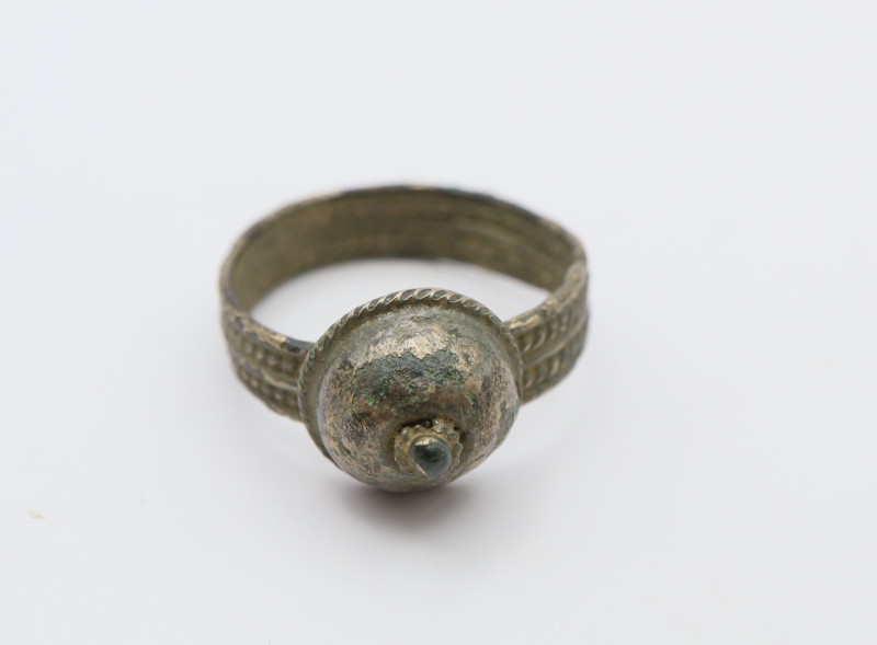 A silvered finger ring with a flat band with decoration; dome shaped bezel; 3.22...