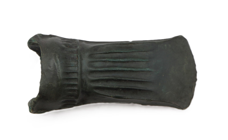 A cast bronze axe head. The head is socketed, with an ovoid opening for a handle...