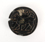 Important élément circulaire représentant un lion surmonté d’une inscription sur une face et un motif végétal à six feuilles sur l’autre
Pierre noire
...