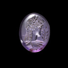 A roman lentoid amethyst with the bust of Apollo in archaistic style. 1st century AD, intact. Amethyst mit Apoll. Römische Kaiserzeit, 1. Jh. v. Chr. ...