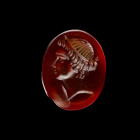 Gemstone with the head of Aphrodite. Hellenistic, late 3rd century BC. 1,4 x 1,1cm. Oval intaglio made of deep red cornelian with plain front and back...