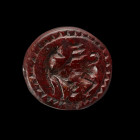 An early archaic round seal made of red serpentine depicting a standing griffin turning his head. Probably attic, about middle 7th century BC, Intact....