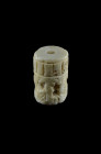 White calcite cylinder seal showing two opposite persons drinking beer with long stalks from a round vessel. Behind two figures and a goat and plant. ...