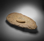 Neolithic grinding mill of oval form with one pointed end made from reddish to yellow stone. Length 51,2cm, width 29,3cm, height 6,7cm. With oval pest...