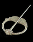 Bronze ring brooch with ribbed hoop, with expanded terminals originally with inlay, the outer edges with hatching, the long flexible pin with ridged l...