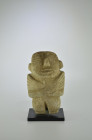 Mezcala, 300 - 100 BC. H 20cm. Gray stone figure with a large head with wedge-shaped nose, the eyes and mouth are notched, the arms crossed in front o...